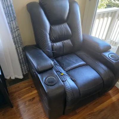 Sale Photo Thumbnail #104: Contemporary black faux-leather home theater power recliner with built-in cup holders and diamond-quilted accent stitching.