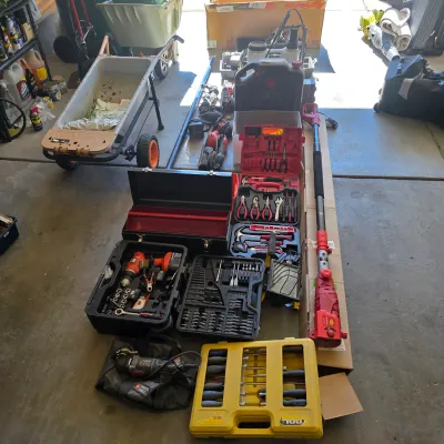 Sale Photo Thumbnail #122: Large assortment of lawn care equipment and power tools, featuring a yard cart, pole saw, and multiple socket and hand tool sets.