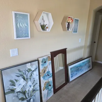 Sale Photo Thumbnail #89: Collection of modern home decor including floral wall art prints, a dark wood framed mirror, framed inspirational signs, and two white hexagonal shadow box shelves.