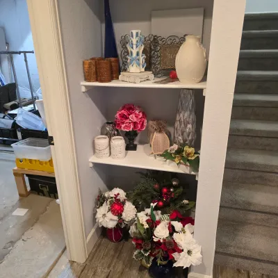 Sale Photo Thumbnail #42: Built-in shelving unit filled with home decor items including decorative vases, artificial floral arrangements, carved candles, and Christmas decorations.