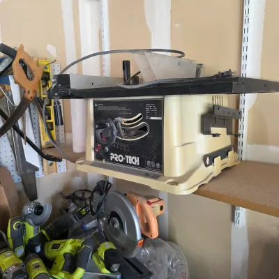 Sale Photo Thumbnail #151: Pro-Tech benchtop table saw with a cream plastic housing, mounted on a workshop shelf alongside assorted power tools.