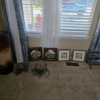 Sale Photo Thumbnail #82: A selection of home decor items, including four framed wall art prints, metallic floral wall sculptures, and a large floor vase arranged near a window.