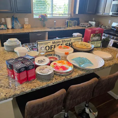 Sale Photo Thumbnail #113: A kitchen island display featuring various dishware, serving platters, a wooden 'Main Street Coffee Shop' sign, and several boxes of Morton ice cream salt.