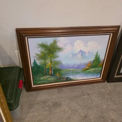 Sale Photo Thumbnail #16: Framed oil painting depicting a scenic mountain landscape with a lake and trees, signed by the artist in the lower left corner.