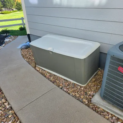 Sale Photo Thumbnail #165: Large outdoor resin deck box in grey and beige, sitting alongside a house exterior.
