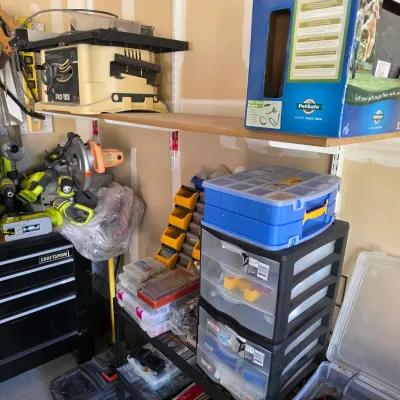 Sale Photo Thumbnail #150: Workshop storage area featuring stacked plastic organizer drawers, small parts bins, power tools, and a benchtop table saw.