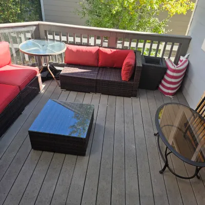 Sale Photo Thumbnail #65: Contemporary outdoor wicker patio set featuring dark brown sectional sofas with red cushions, a matching glass-top coffee table, and auxiliary glass-top accent tables on a wooden deck.
