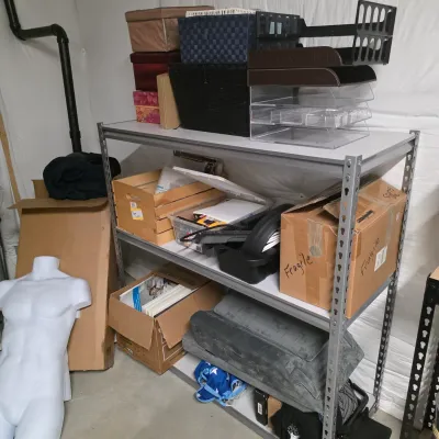 Sale Photo Thumbnail #56: Metal shelving unit holding various storage boxes, office organizers, and supplies, positioned alongside a white male torso mannequin.