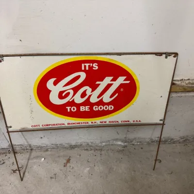 Sale Photo Thumbnail #9: Lot009 Vintage "It's Cott To Be Good" Metal Advertising Sign with Wire Stand – Cott Corporation, Manchester, N.H