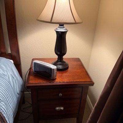 Sale Photo Thumbnail #133: Traditional dark wood two-drawer nightstand topped with a turned dark urn table lamp and a digital alarm clock.