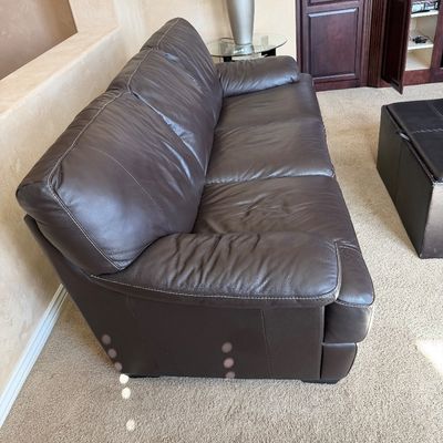 Sale Photo Thumbnail #230: Contemporary dark brown leather sofa featuring contrast stitching and padded armrests.