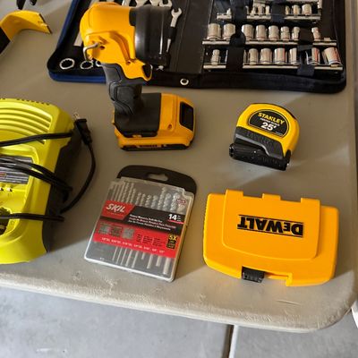 Sale Photo Thumbnail #81: Assorted modern hand tools and accessories, including a DeWalt cordless work light, Stanley tape measure, Skil drill bit set, and a socket set.