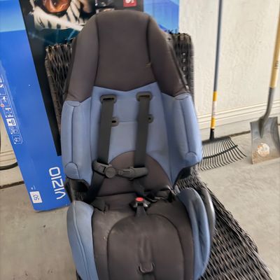 Sale Photo Thumbnail #85: Blue and black toddler car seat with five-point harness resting on a wicker patio chair.