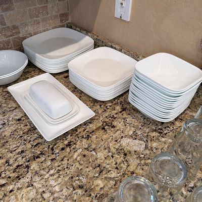 Sale Photo Thumbnail #192: Collection of white modern square dinnerware, including stacks of plates, salad bowls, a covered butter dish, and accompanying glassware.