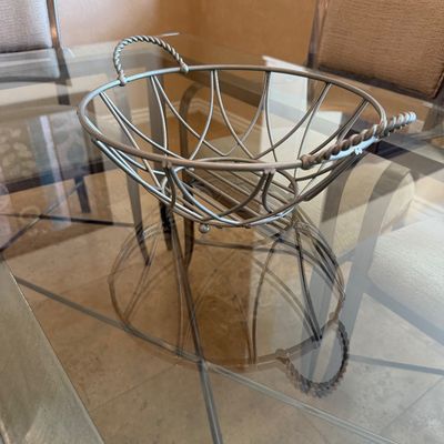 Sale Photo Thumbnail #207: Silver-tone wire basket with twisted rope-style side handles, resting on a glass dining table.