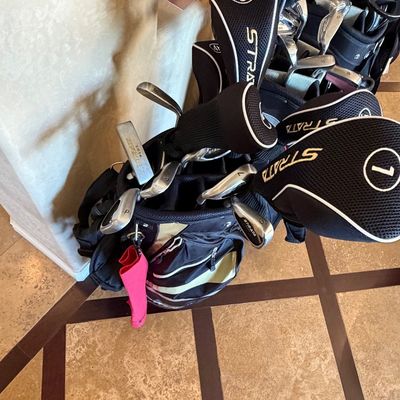 Sale Photo Thumbnail #256: Strata golf club set inside a black stand bag, featuring various irons, putter, and woods with headcovers.