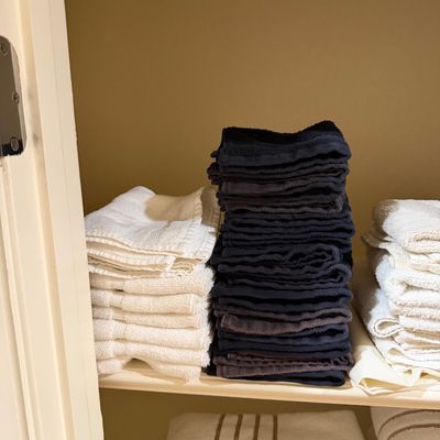 Sale Photo Thumbnail #151: Neatly folded stacks of bath linens, washcloths, and hand towels resting on closet shelves.