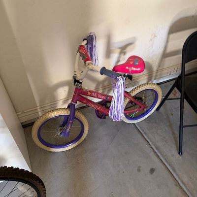 Sale Photo Thumbnail #103: Avigo 'Lil Gem' pink and purple child's bicycle, featuring handlebar streamers and a padded seat, showing light wear.