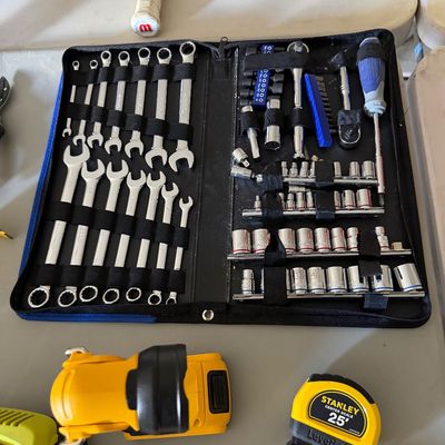 Sale Photo Thumbnail #74: Portable mechanics tool set in a zippered black case, displayed alongside a Stanley LeverLock 25-foot tape measure and power tool accessories.