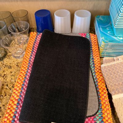 Sale Photo Thumbnail #161: Collection of kitchen and dining items, including woven colorful placemats, microfiber drying mats, plastic cups, glassware, and patterned melamine plates.