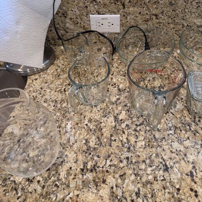 Sale Photo Thumbnail #193: Collection of clear glass kitchenware including Anchor Hocking glass measuring cups, mixing bowls, and a jar arranged on a granite countertop.