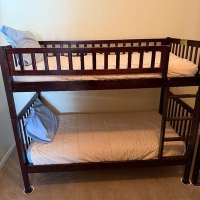 Sale Photo Thumbnail #61: Dark wood twin-over-twin bunk bed set with an attached side ladder, upper safety guardrails, mattresses, and bedding.