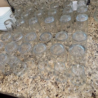 Sale Photo Thumbnail #191: Large collection of clear vintage glassware resting upside down on a granite kitchen countertop, featuring various sizes of textured drinking glasses.