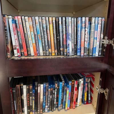 Sale Photo Thumbnail #222: Large collection of DVDs and Blu-ray movies organized on shelves inside a dark wood cabinet.