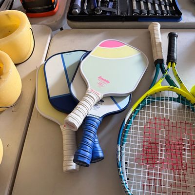 Sale Photo Thumbnail #91: Collection of sports equipment and tools, featuring several Franklin pickleball paddles, tennis racquets, and a organized socket and wrench set in the background.