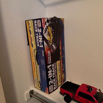 Sale Photo Thumbnail #54: Auto World 2-in-1 electric slot car race track set in original box, sitting on a closet shelf next to a red toy pickup truck.