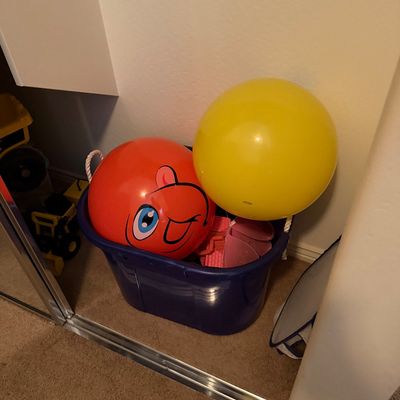 Sale Photo Thumbnail #59: Blue plastic storage bin filled with children's play balls and miscellaneous toys, including a large red ball with a printed cartoon face.