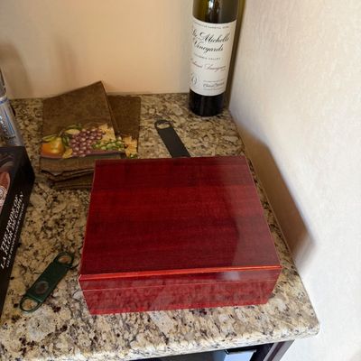 Sale Photo Thumbnail #44: Polished cherry wood humidor shown on a granite countertop alongside cigar accessories and a bottle of Chateau Ste. Michelle wine.