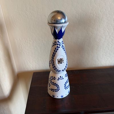 Sale Photo Thumbnail #34: Hand-painted Clase Azul Reposado tequila ceramic decanter with signature silver bell topper, standing on a dark wood console table.