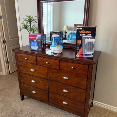 Sale Photo Thumbnail #126: Traditional dark wood nine-drawer dresser with attached matching framed mirror, displayed with small appliances including a humidifier and space heater.
