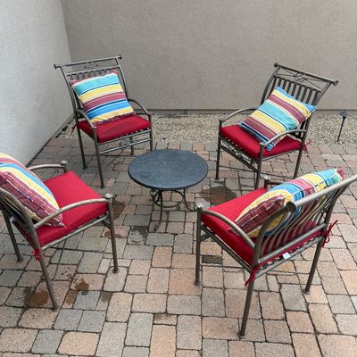 Sale Photo Thumbnail #7: Five-piece metal patio set featuring four armchairs with red seat cushions and striped throw pillows, alongside a small round side table.