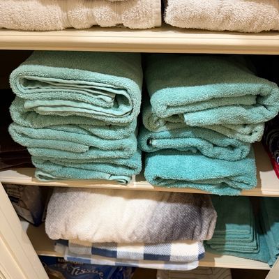 Sale Photo Thumbnail #143: Linen closet filled with neatly stacked terry cloth bath towels, hand towels, and washcloths in shades of white, teal, and aqua, along with folded plush blankets.