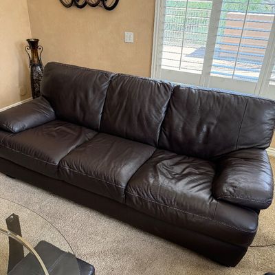 Sale Photo Thumbnail #233: Contemporary dark brown leather sofa featuring contrast stitching and padded armrests.