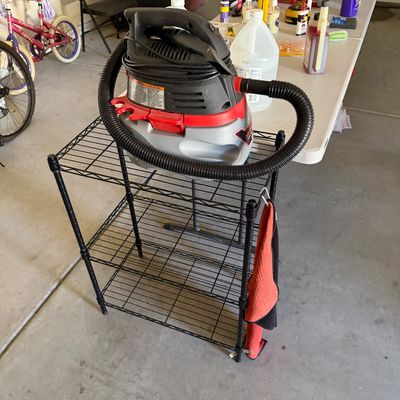 Sale Photo Thumbnail #96: Craftsman wet/dry shop vacuum resting on a three-tier black wire utility cart inside a garage setup.