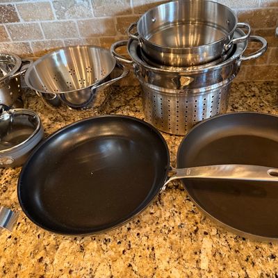 Sale Photo Thumbnail #182: Assortment of modern cookware, including nonstick skillets, stainless steel strainers, colanders, and stock pots displayed on a kitchen countertop.