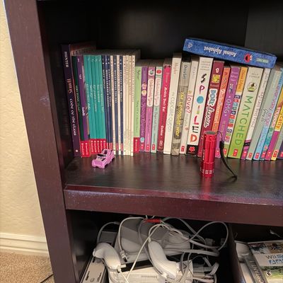 Sale Photo Thumbnail #68: Dark wood bookcase filled with various children's and young adult chapter books, including American Girl titles, along with a Nintendo Wii console and accessories.