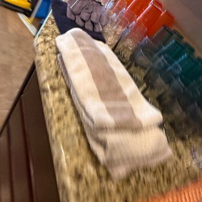Sale Photo Thumbnail #55: Collection of assorted kitchen towels, work gloves, and colorful plastic and glass drinkware set on a granite countertop.
