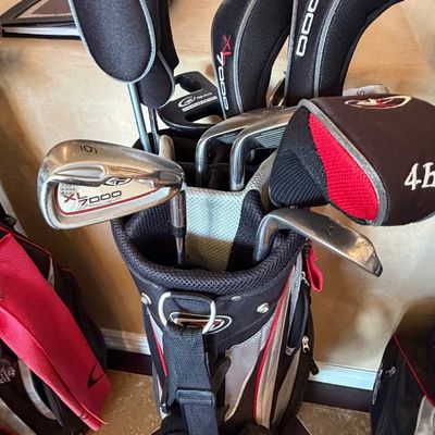 Sale Photo Thumbnail #259: Top-Flite XL 7000 golf club set in a black and red cart bag, featuring irons, woods, and putter with matching headcovers.