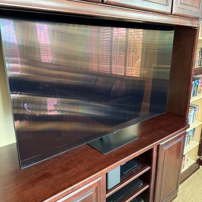 Sale Photo Thumbnail #217: Large flat-screen television situated inside a traditional cherry wood entertainment center with lower media components.