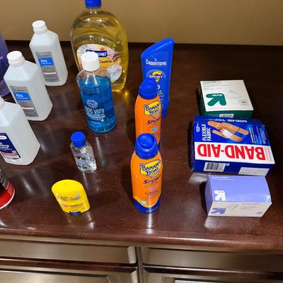Sale Photo Thumbnail #144: Assortment of personal care and first aid items including Banana Boat sunscreen, Band-Aid bandages, Up & Up alcohol swabs, rubbing alcohol, and liquid soap.