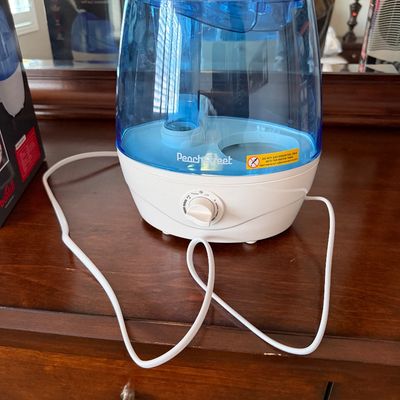 Sale Photo Thumbnail #124: PeachStreet cool mist humidifier with a blue water tank and white base, featuring a front control knob.