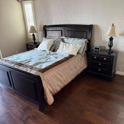 Sale Photo Thumbnail #19: Dark wood sleigh bed set featuring matching three-drawer nightstands and bedside lamps in a contemporary style.