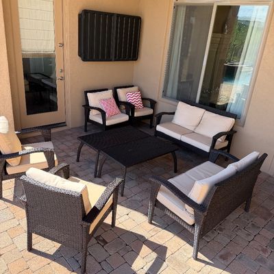 Sale Photo Thumbnail #244: Outdoor patio furniture set featuring dark brown resin wicker armchairs, loveseats, and matching coffee tables with off-white seat cushions.