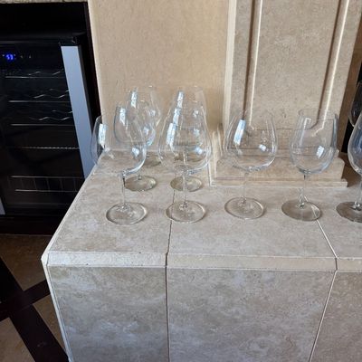 Sale Photo Thumbnail #39: Collection of clear glass wine goblets displayed on a tiled countertop next to a wine cooler.
