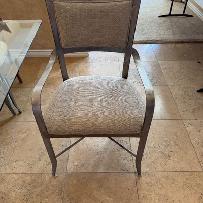 Sale Photo Thumbnail #215: Contemporary metal arm chair with beige textured fabric upholstery on the seat and backrest.