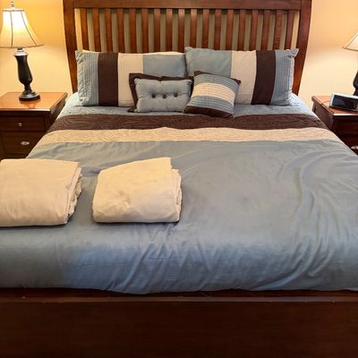 Sale Photo Thumbnail #134: Wooden slatted headboard and bed frame set with light blue and brown bedding, decorative pillows, and folded linens.